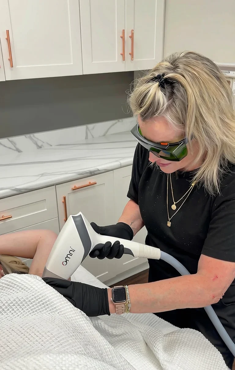 Practitioner using Omni handheld device to perform laser treatment on client's leg